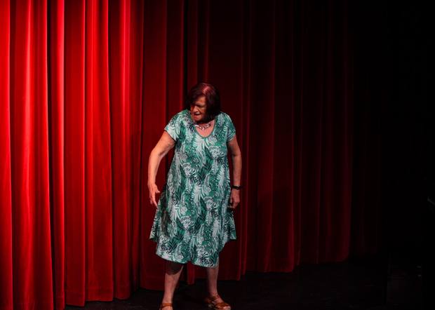 Alumna en escena ante el telón rojo
